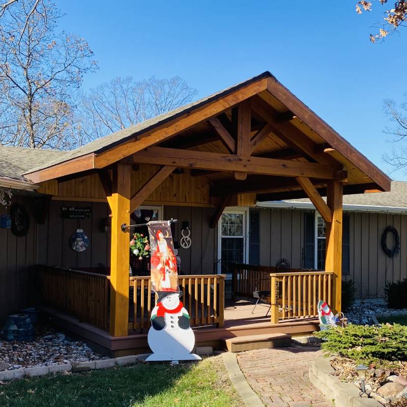 a wooden porch with a christmas tree and a snowman